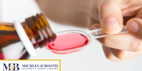 Prescription syrup being poured into a teaspoon.