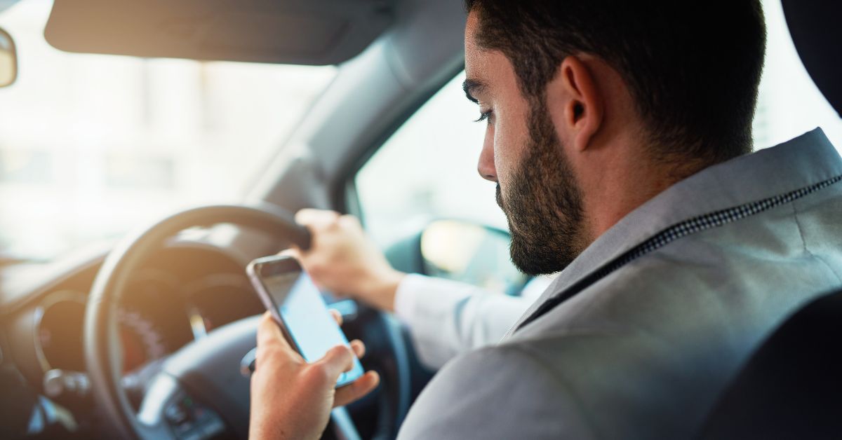 man looking at phone while driving
