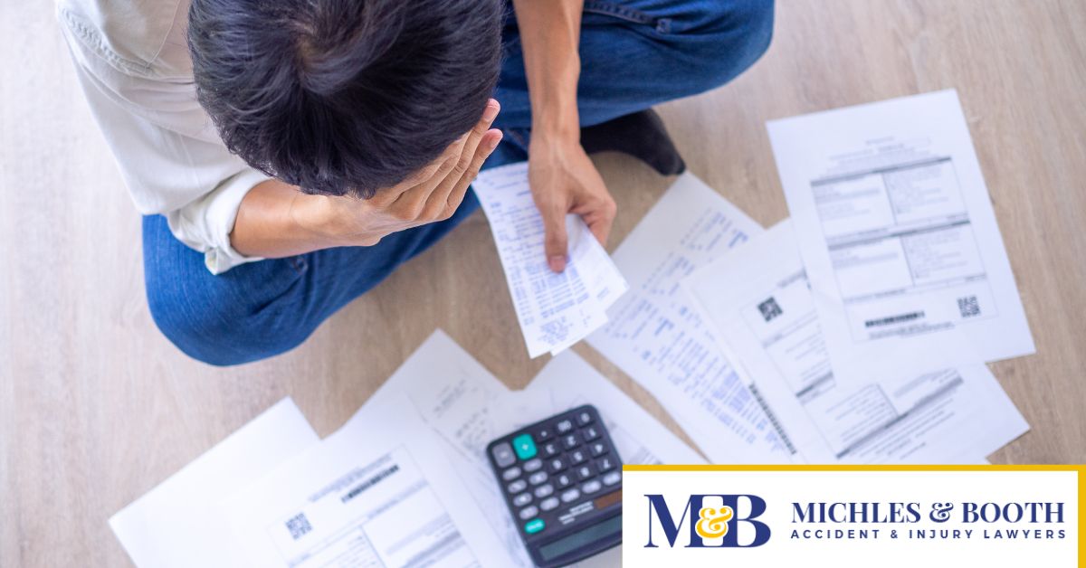 Picture of man from above sitting on floor looking at a calculator and bills.